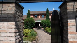 A brick pathway leading to a building with a tiled roof and a gate.