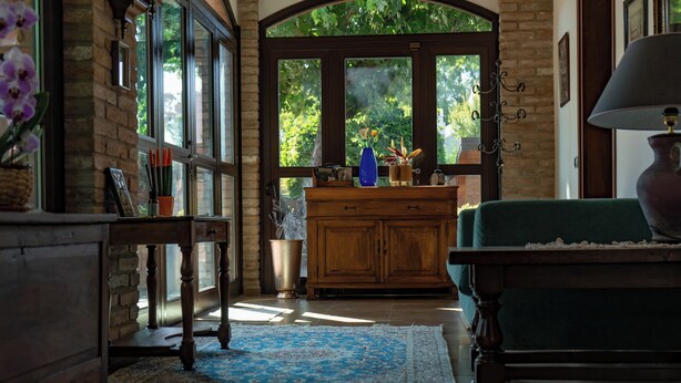 A cozy room with a wooden cabinet, a green sofa, and a window with a view of greenery.