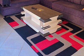 A modern living room with a unique coffee table design, a patterned rug, and a purple sofa. - Kampala - Sleeps 2 - Apartment - Parking (Kampala)
