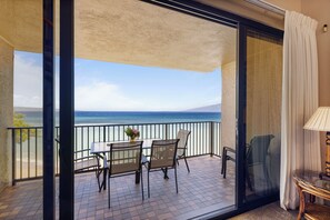 Enjoy breathtaking ocean views and mountain vistas from this balcony with a table and chairs.