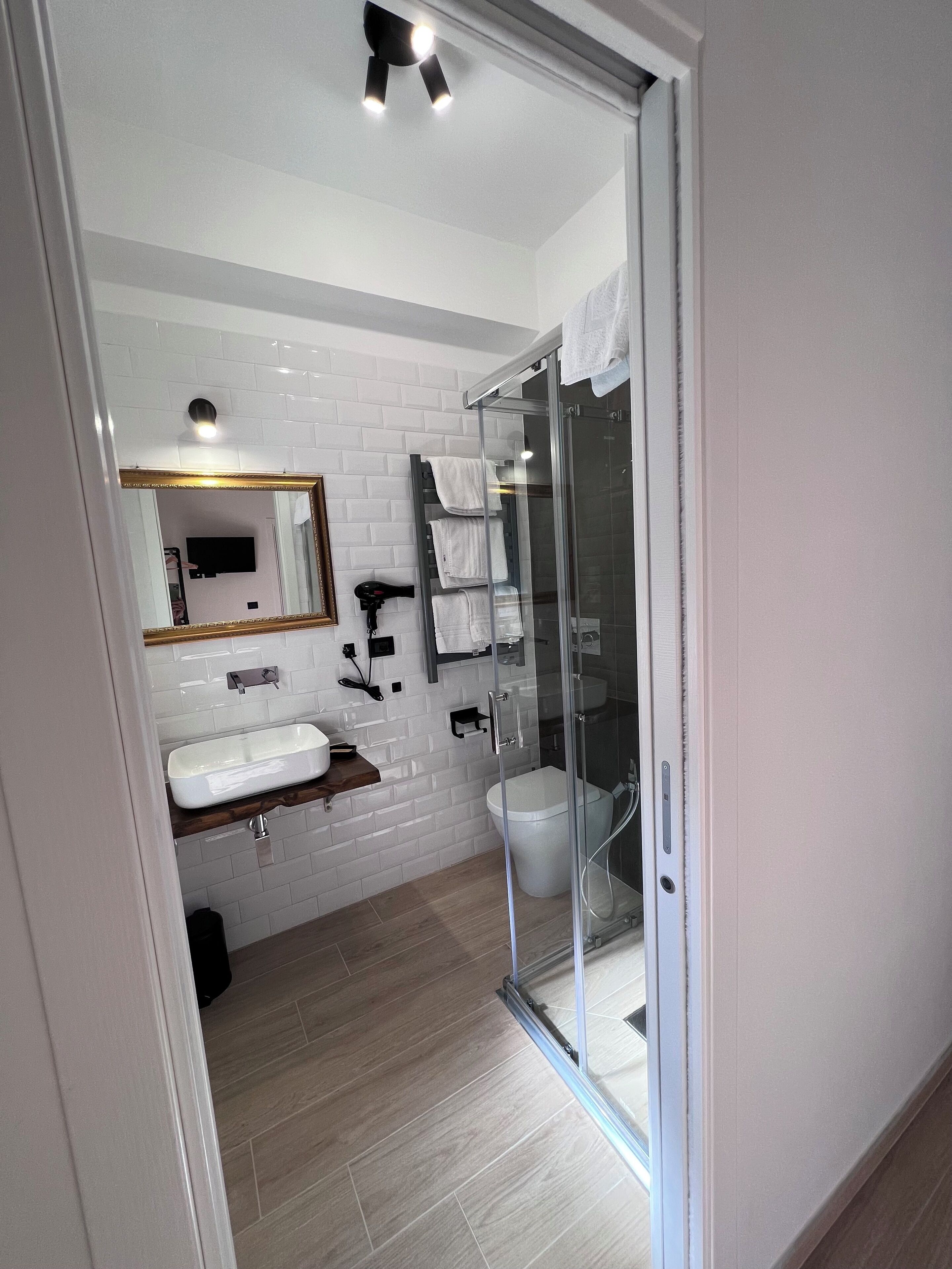 Un bagno moderno con box doccia in vetro, lavandino bianco e specchio.