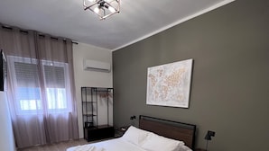 Een netjes opgemaakt bed met witte lakens, een houten hoofdbord en een nachtkastje met een lamp.