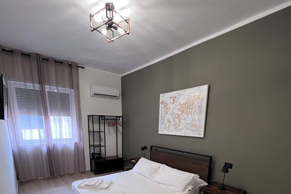 A neatly made bed with white linens, a wooden headboard, and a bedside table with a lamp.