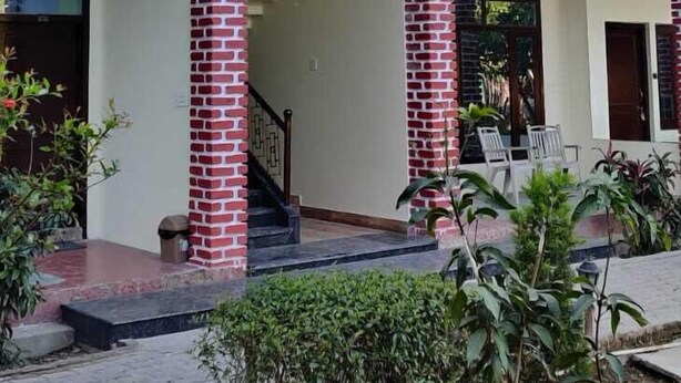 Un edificio a due piani con un balcone, colonne in mattoni e una tettoia.