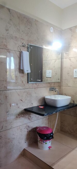 A bathroom with a white sink, a mirror, and a towel rack. - Karans corbett motel (Ramnagar)