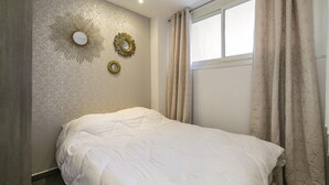 A bedroom with a bed, a window with curtains, and wall decorations. - CIOLLI (Cannes)