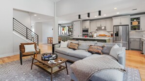 A spacious living room with a grey sofa, a coffee table, and a staircase.