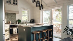 Una cocina moderna con una isla grande, taburetes de bar, estufa y cafetera.