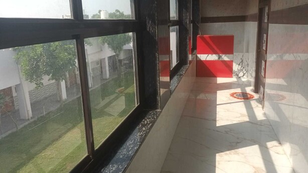 Un couloir doté de grandes fenêtres, d’un sol carrelé et d’un mur d’accent de couleur rouge.