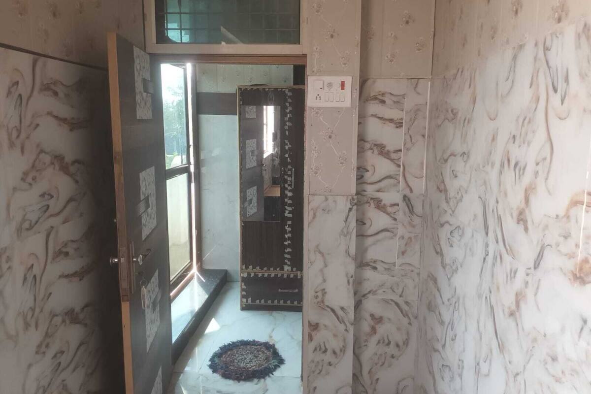 A hallway with patterned walls, a door leading to a room, and a rug on the floor.