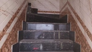 Un escalier aux murs de marbre et aux marches sombres.