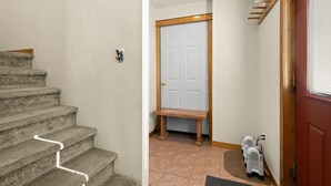 A staircase leading to a door with a bench, a small rug, and a heater on the floor.