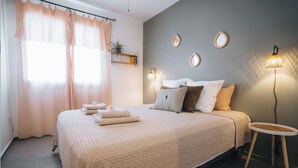 Un dormitorio con una cama grande, una mesita de noche, una lámpara y un ventanal con cortinas.