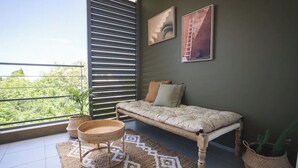 Un balcón con una cama, una cesta tejida y una planta en maceta.