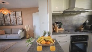 Una cocina moderna con comedor, que incluye un cuenco de frutas, dos vasos de jugo de naranja y un adorno en la pared.