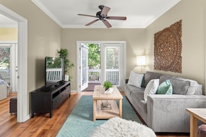 A living room with a grey sofa, wooden coffee table, and a TV on a black stand. - Mermaid's Retreat at Coral Hammock Spacious 3BR Near Key West + Pool (Key West)