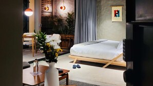 A modern bedroom with a bed, a desk, and a chair. There are plants and a painting on the wall. - w Dazzling Loft w Majestic Deco in Poblado (Medellín)