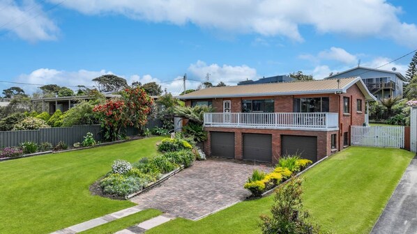 Une maison à deux étages avec un balcon, un garage et un jardin bien entretenu.
