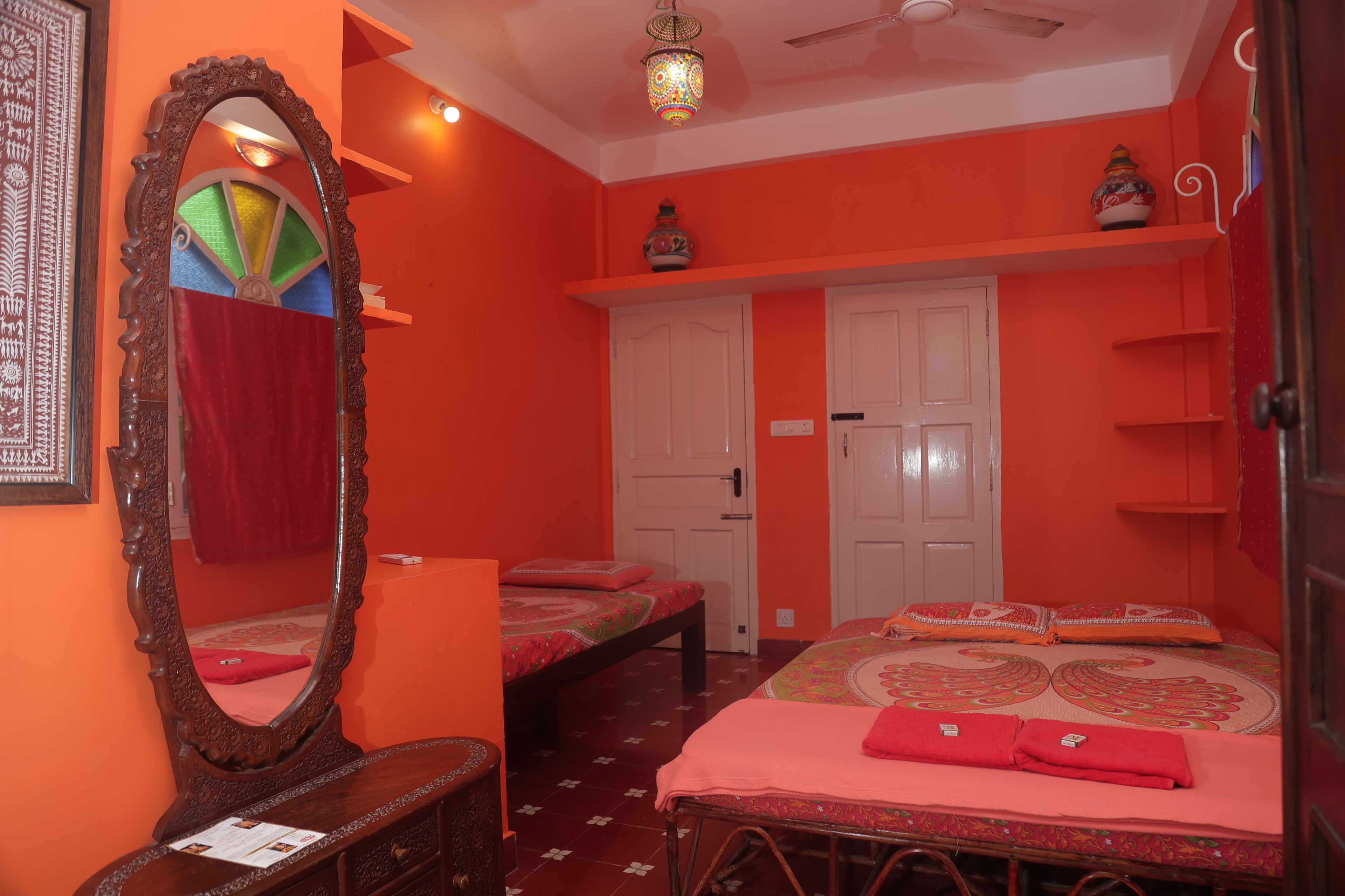 A room with two beds, a dresser, a mirror, and a ceiling fan.