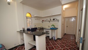 Une cuisine de taille réduite avec un îlot central, des murs blancs et des carreaux de sol à motifs.