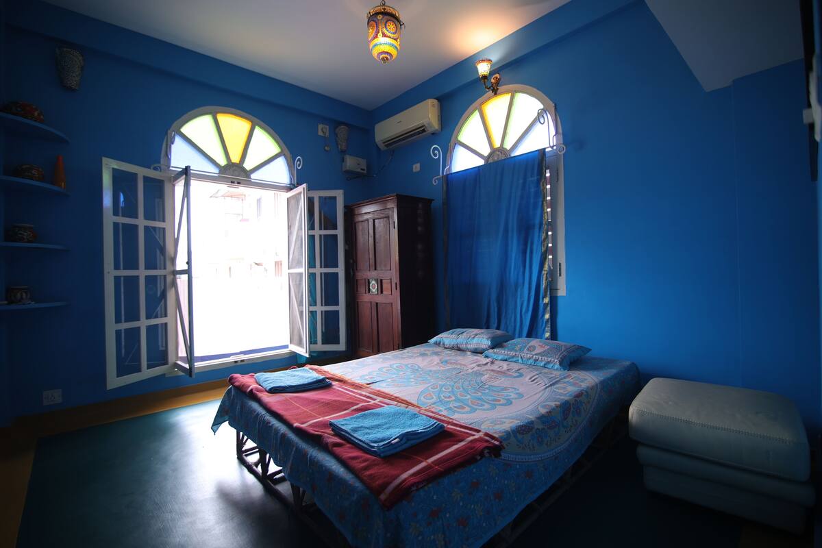 Een kamer met een bed, een bankje en een kledingkast.