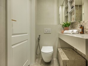 Un bagno con il water, una doccia, un lavandino con uno specchio e un portasciugamani.