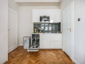 A compact kitchen with white cabinets, a built-in oven, and a dishwasher.