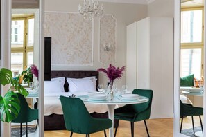 Una habitación de hotel moderna con cama, una mesa de comedor para cuatro comensales y una araña.