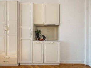 A kitchen with white cabinets, a countertop, and a stainless steel range hood.