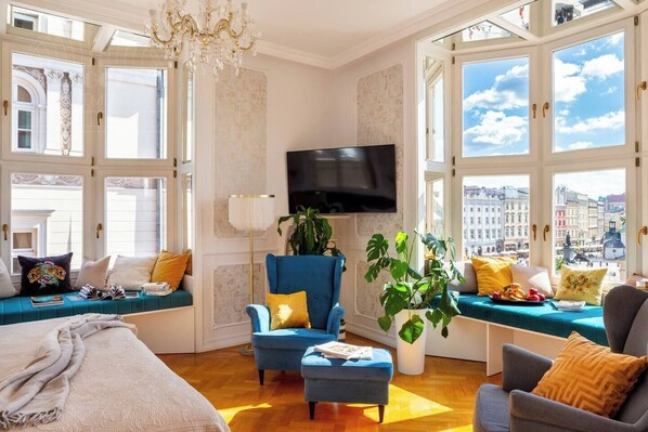 A room with a large window, a television, a sofa, a chair, and a plant.