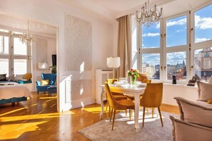 A spacious room with a dining area, a large window with a city view, and a chandelier. - Feniks Lagoon apartment -the best Main Square view (Kraków - Feniks)