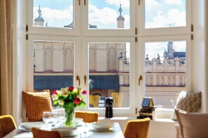 Ein Essbereich mit Tisch für vier Personen, einer Blumenvase und Blick auf ein historisches Gebäude mit Kuppeln.