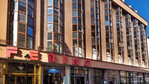 Un edificio de varios pisos con un llamativo letrero de 'FEDINE' en la planta baja, que cuenta con escaparates de vidrio y una entrada visible.