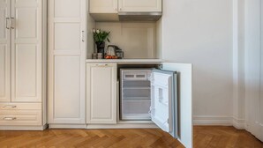 Una cocina con armarios blancos, horno empotrado y refrigerador.