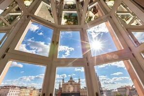 A high-ceilinged room with multiple skylights, a view of a historic building, and a clear sky.