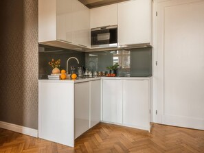 A compact kitchen with white cabinetry, a microwave, and a sink.