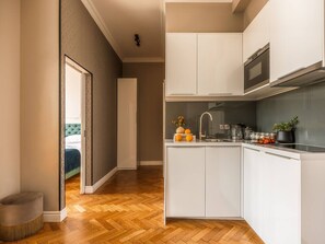 Une cuisine de taille réduite avec des meubles blancs, un four à micro-ondes et un évier.