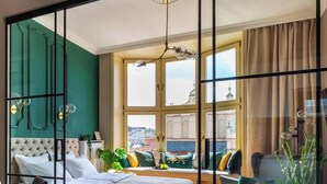 Un dormitorio con una cama grande, un escritorio, una silla y una ventana con vistas a la ciudad.