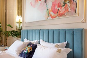 A bed with a teal upholstered headboard, white pillows, and a decorative pillow with a floral design. - Feniks Indigo studio with a Main Square view (Kraków - Feniks)