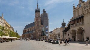 A historic square with a prominent church, a statue, and a covered market area.