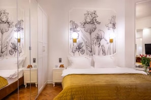 Une chambre d’hôtel avec un grand lit, une table de chevet, une commode, un miroir et un mur décoré d’œuvres d’art florales.