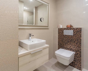 Une salle de bain avec un lavabo blanc, un miroir, des toilettes et un mur décoratif.