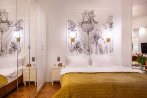 Ein Hotelzimmer mit einem großen Bett, einem Nachttisch, einem Spiegel und einer Wand mit floralen Bildern.
