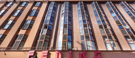 A building with the sign 'FENIKS' on the ground floor, featuring large windows and a modern architectural style.