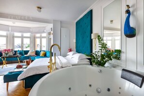 A modern hotel room with a large bathtub, a teal accent wall, and a view of the city. - Feniks Jacuzzi Time studio (Kraków - Feniks)