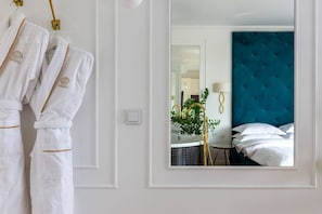 A hotel room with a mirror reflecting a bed, a round sink, and a small table with a plant.