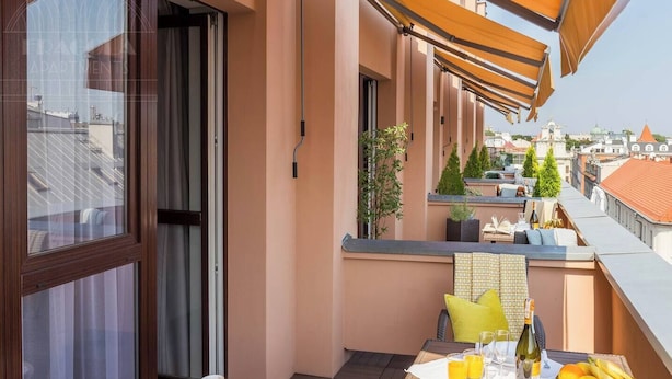 Un balcón con mesa dispuesta para el desayuno, una ventana con cortinas y vistas a la ciudad.