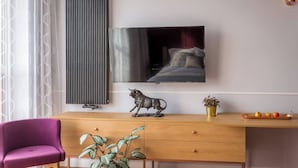 Una sala de estar moderna con un escritorio de madera, una silla morada, una planta en maceta, una estatua de toro, un televisor de pantalla plana y un radiador.