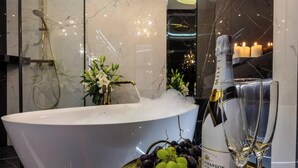 A modern bathroom with a freestanding bathtub, a champagne bottle, and a glass.