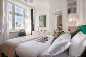 A hotel room with a large bed, a desk, a chair, a mirror, and a window with curtains. - Feniks Smaragd studio - no view (Kraków - Feniks)